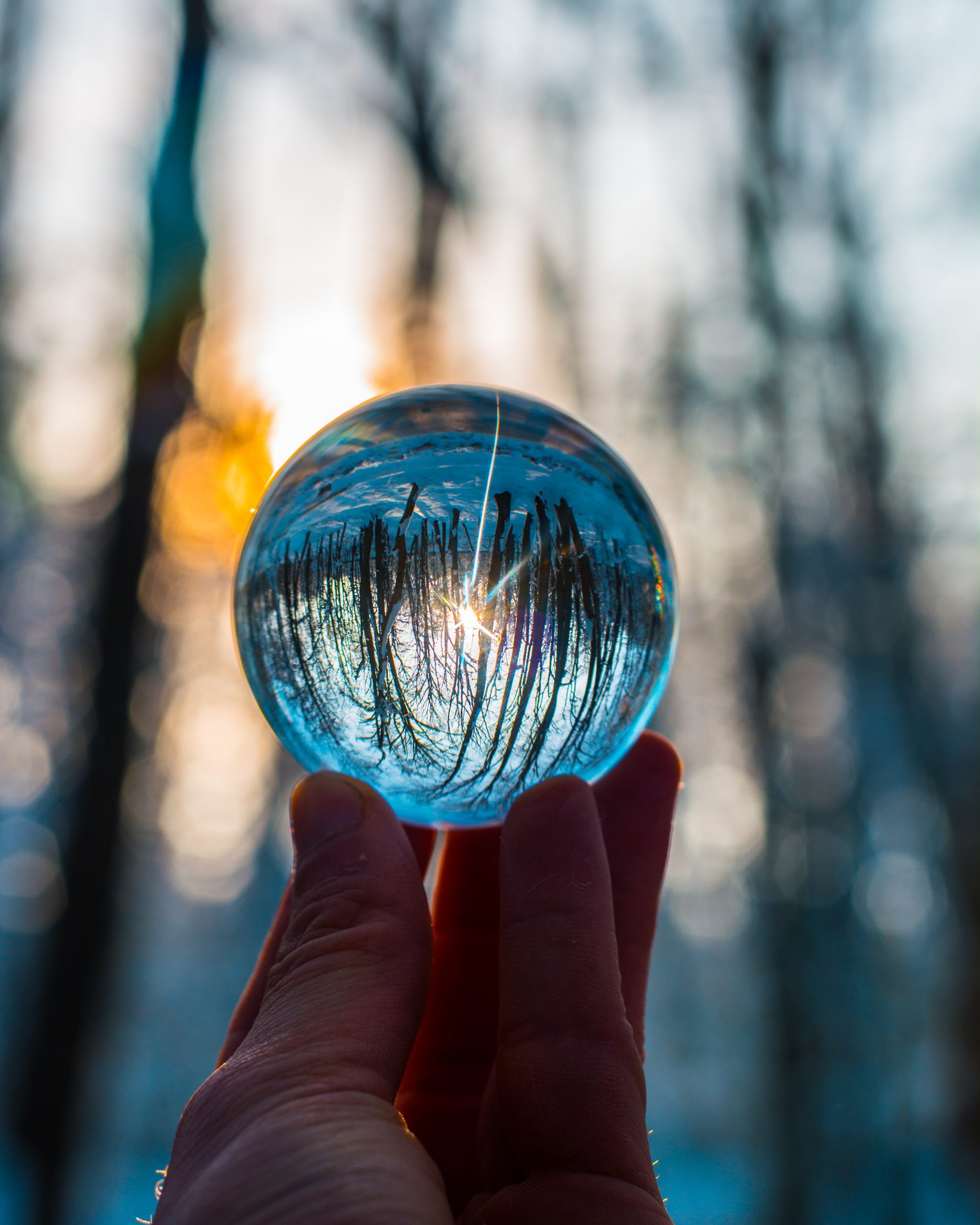 small glass ball on fingertips in woods