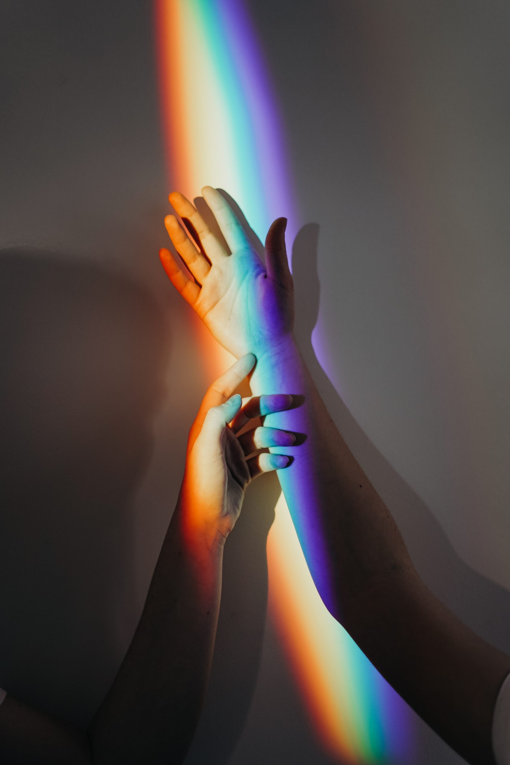 prism rainbow light over hands
