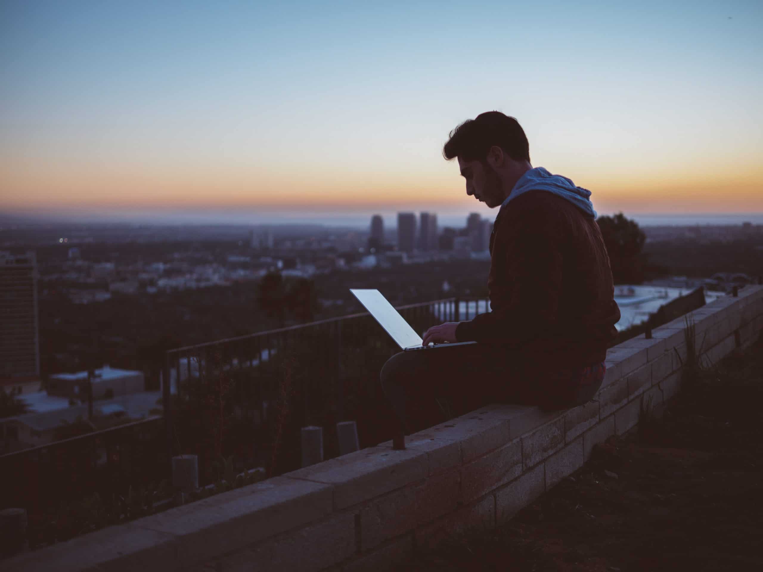 man sitting on rooftop with laptop