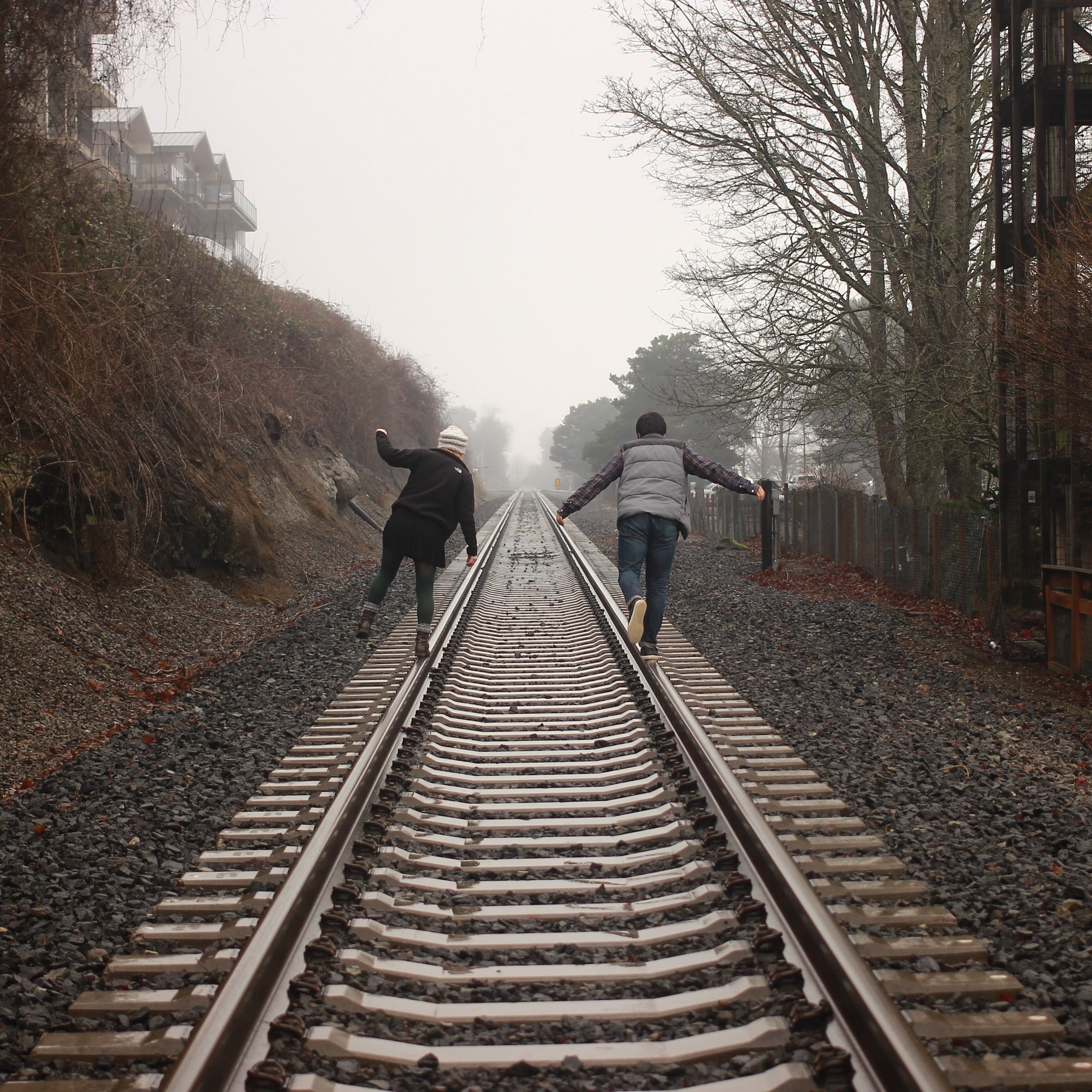 couple walking on train tracks in the mist