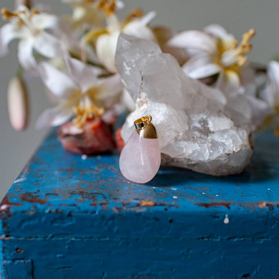 polished rose quartz pendant next to rock crystal