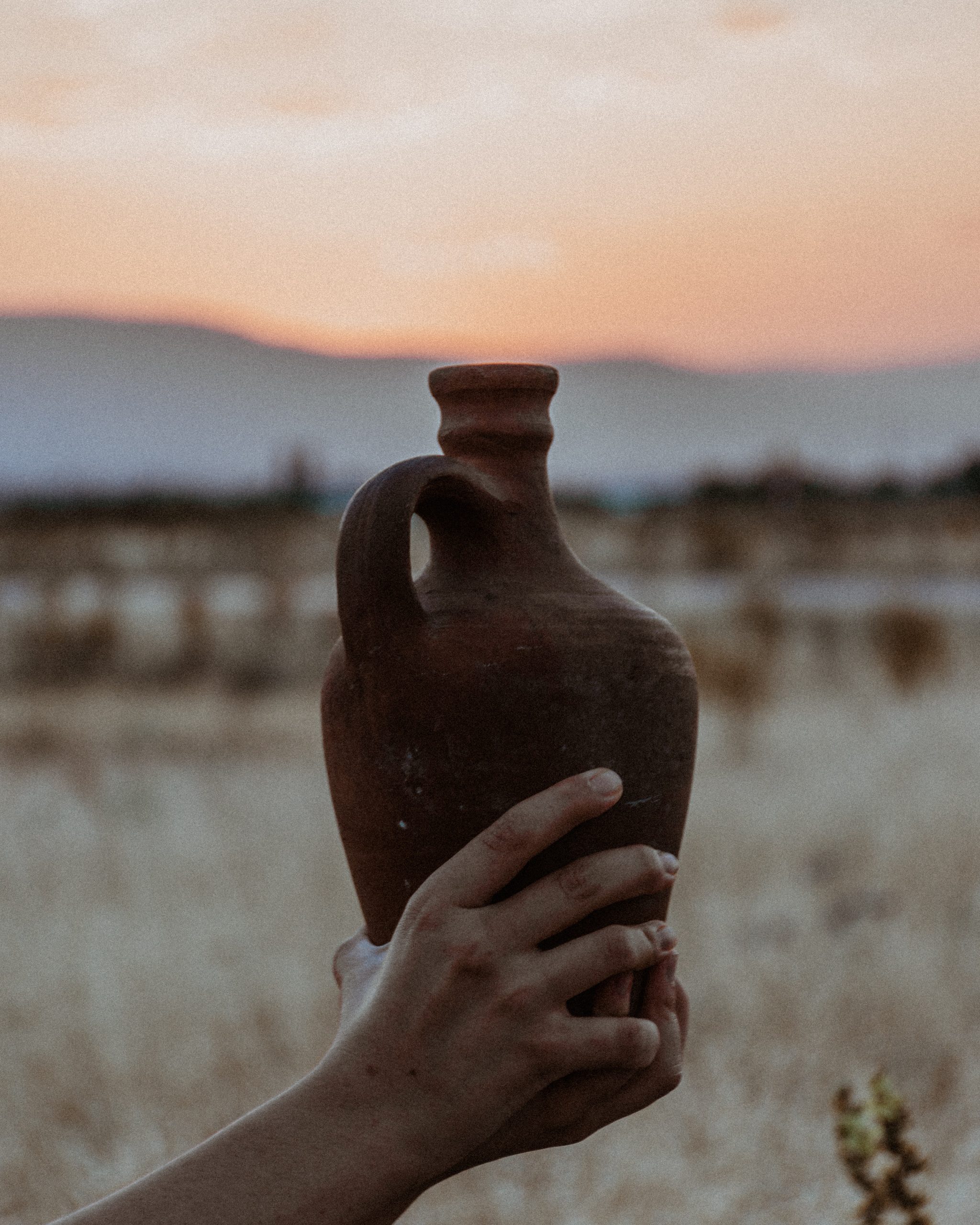 hands holding water jug in sunset
