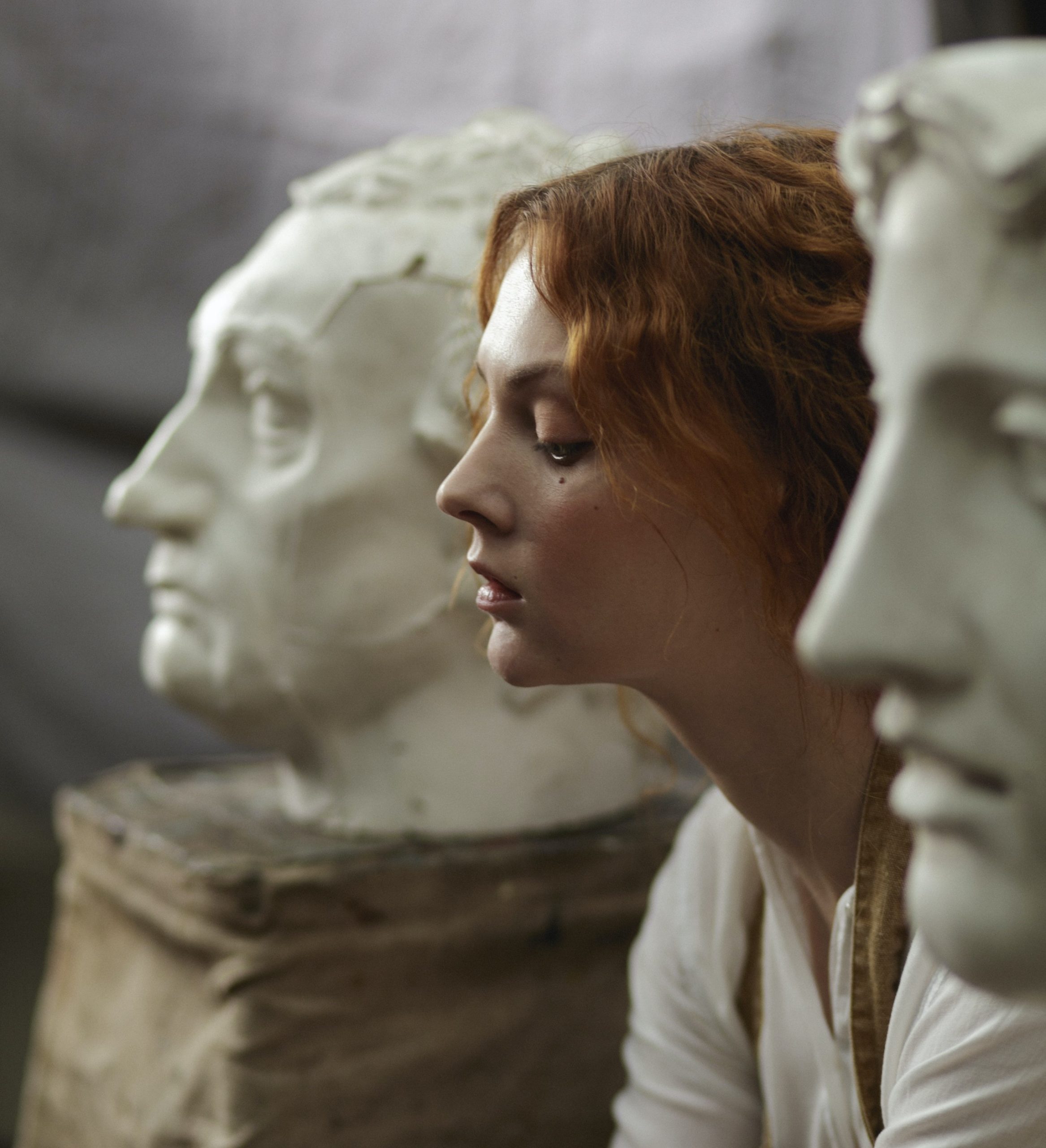 woman sitting between philosopher marble busts