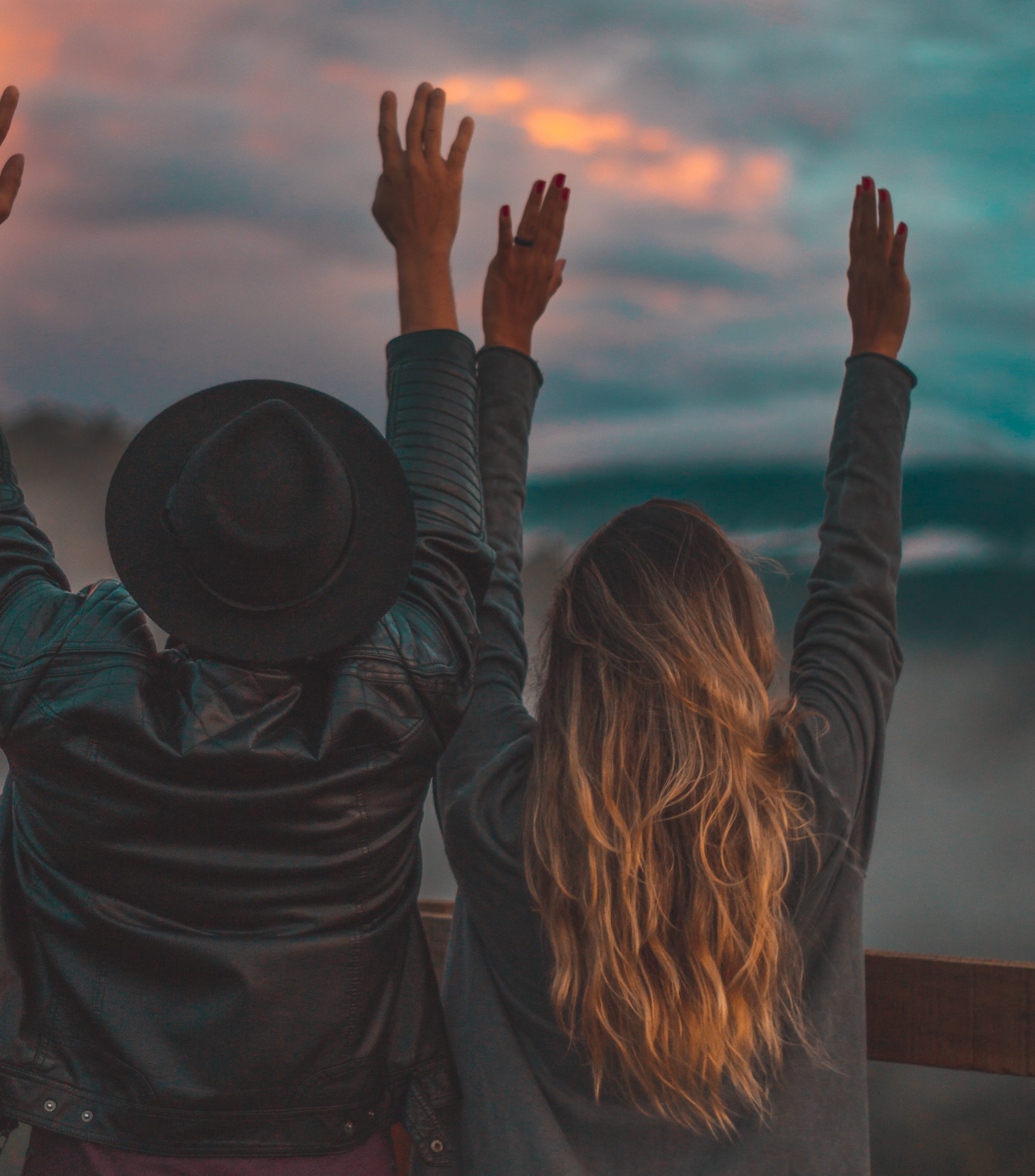 couple arms up sunset 