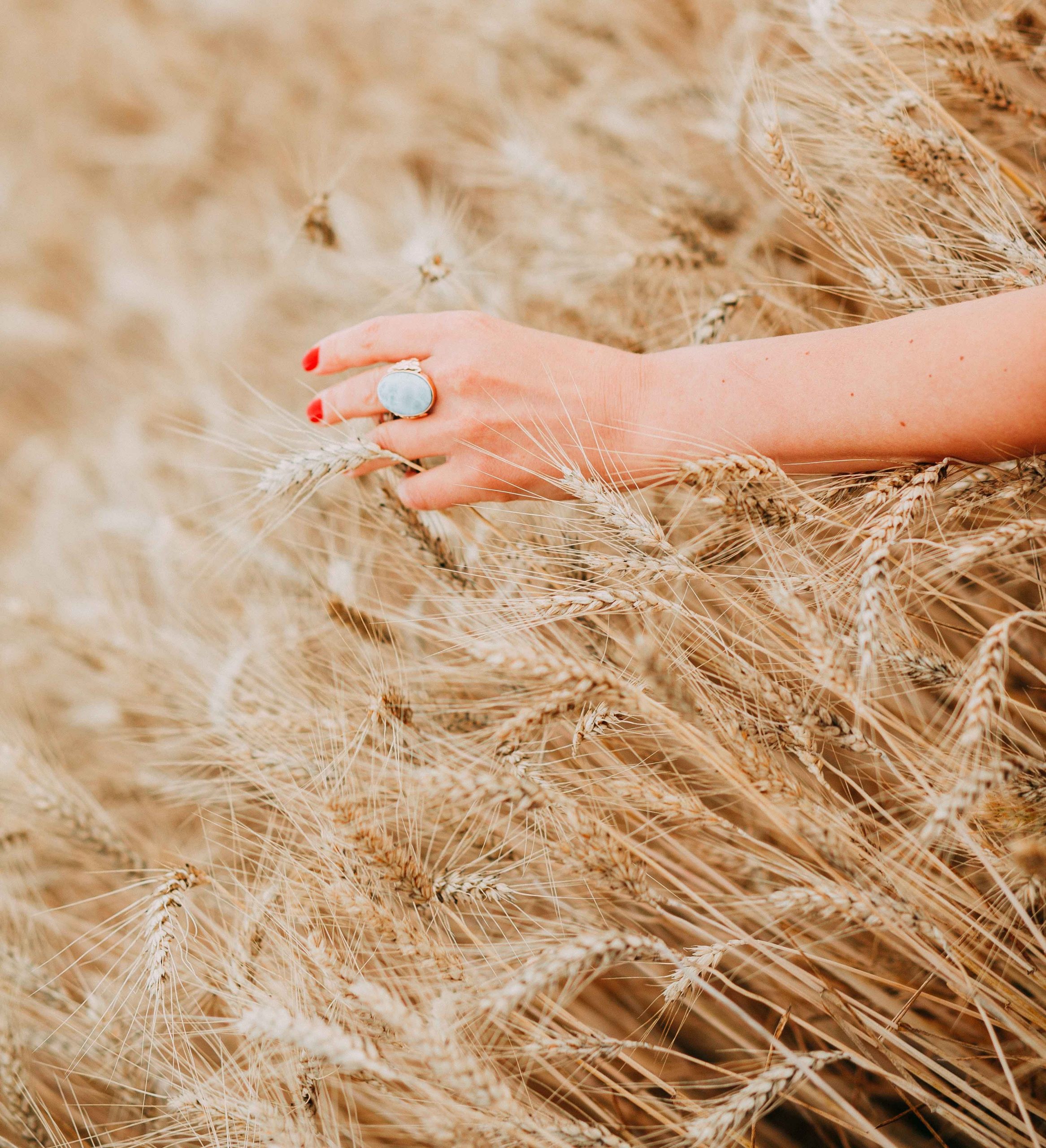 woman's hand white gemstone ring in wheat field