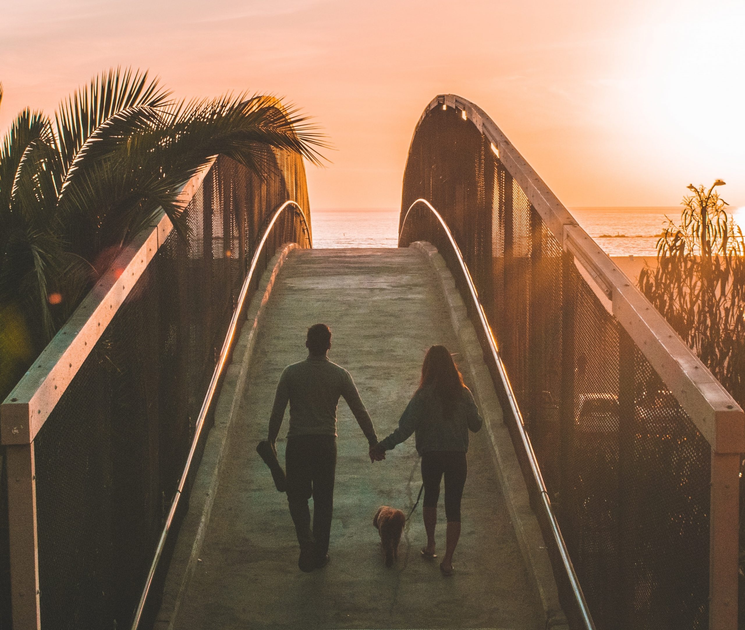 couple crossing bridge at sunset