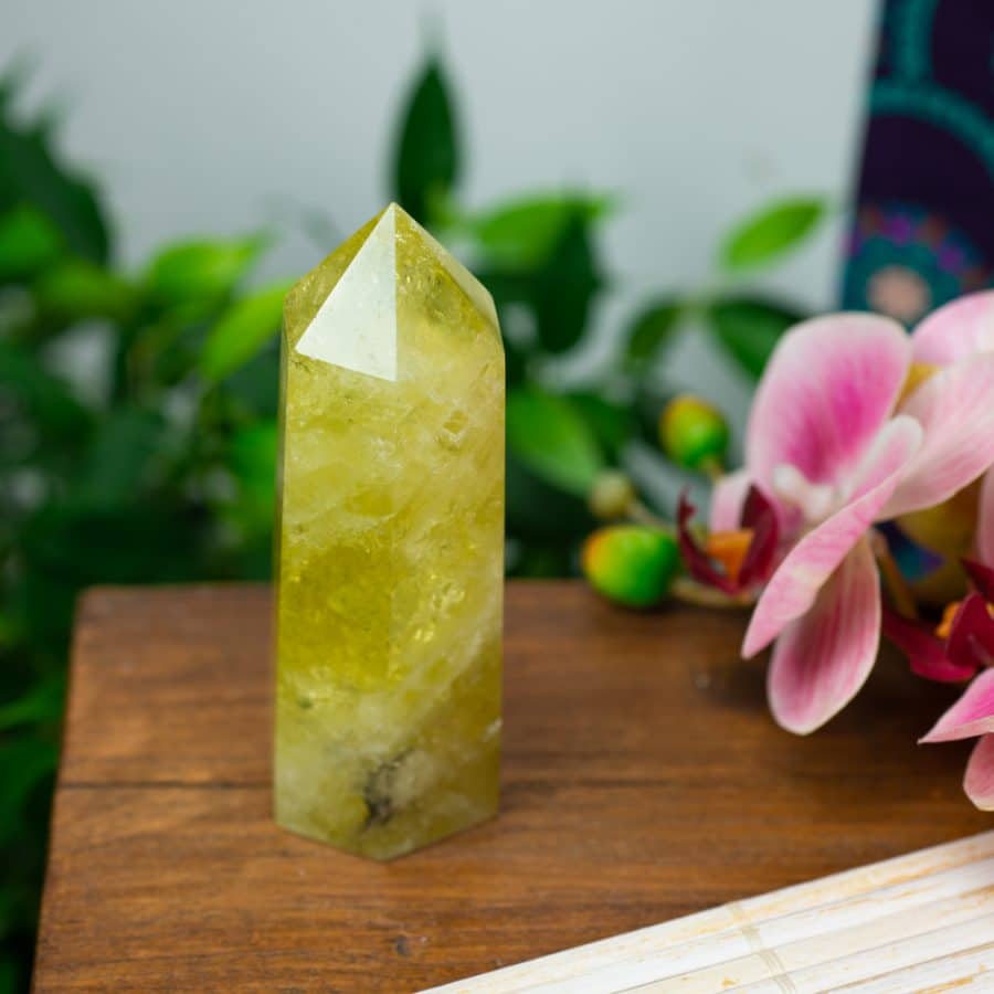 citrine crystal point on table with orchid