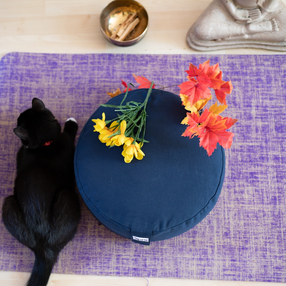 round spiru blue meditation cushion on purple yoga mat palo santo and buddha statue