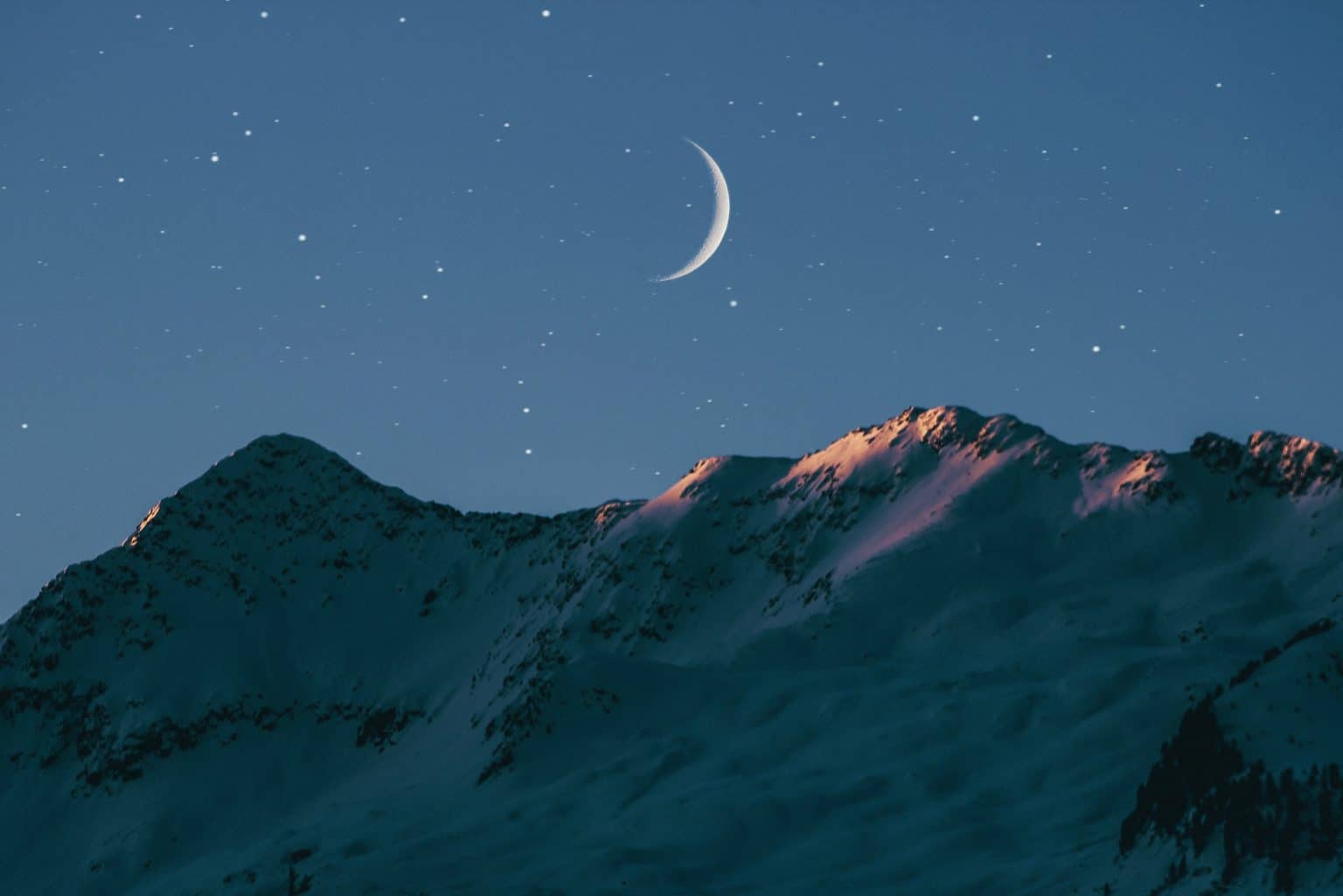 waxing crescent moon over mountains