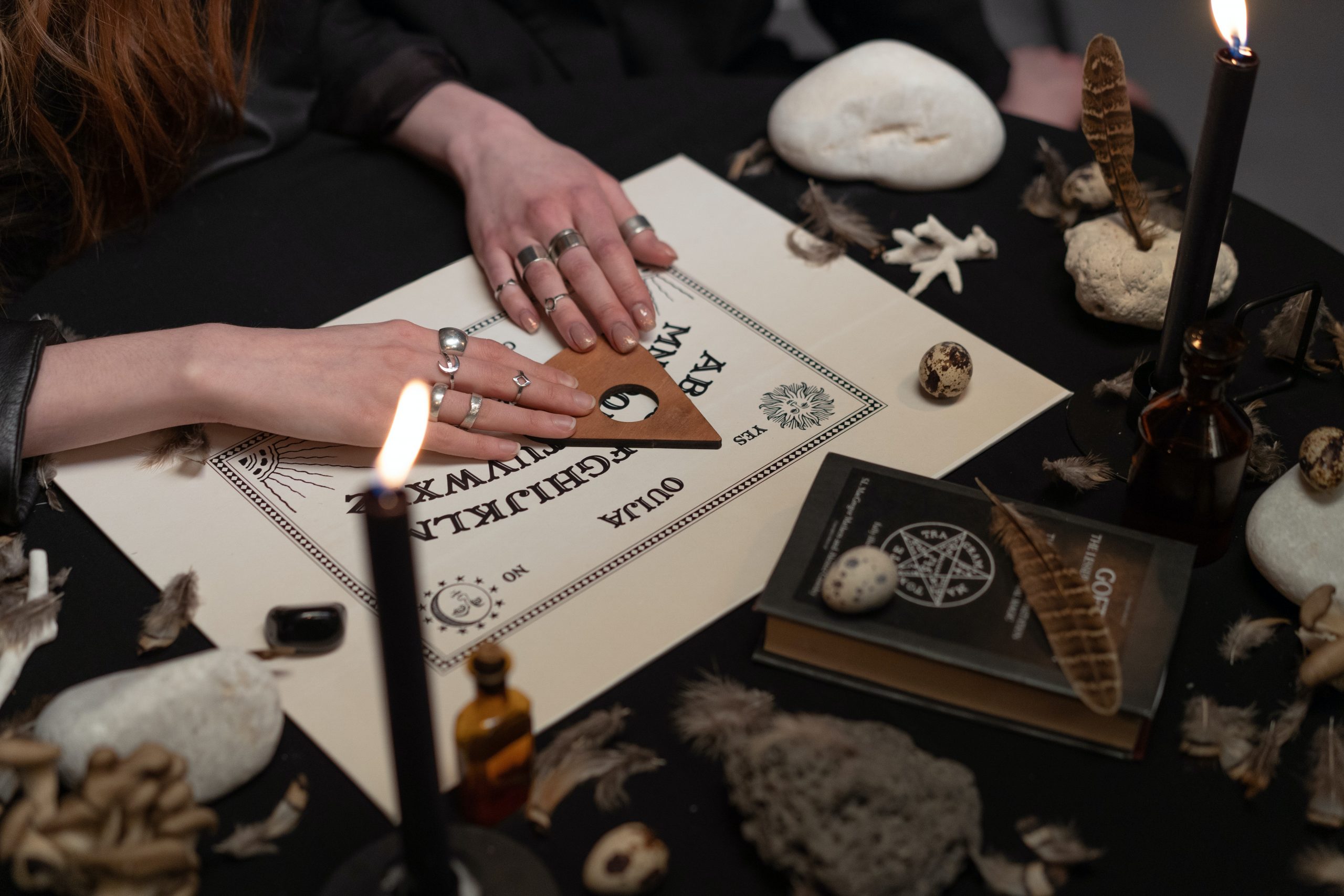 ouija board with crystals and black candles magic book feathers