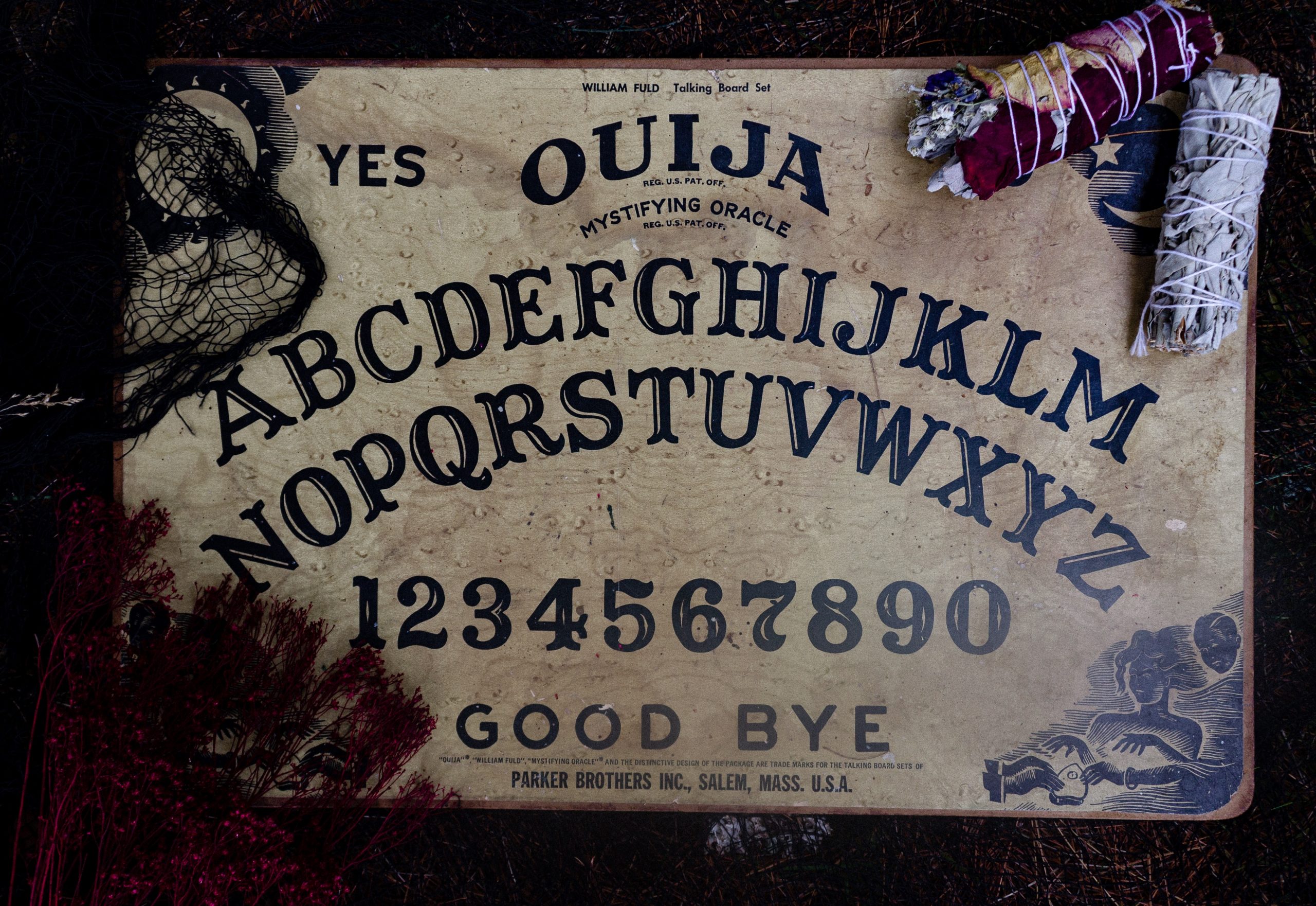 ouija board with white sage smudge and herbs