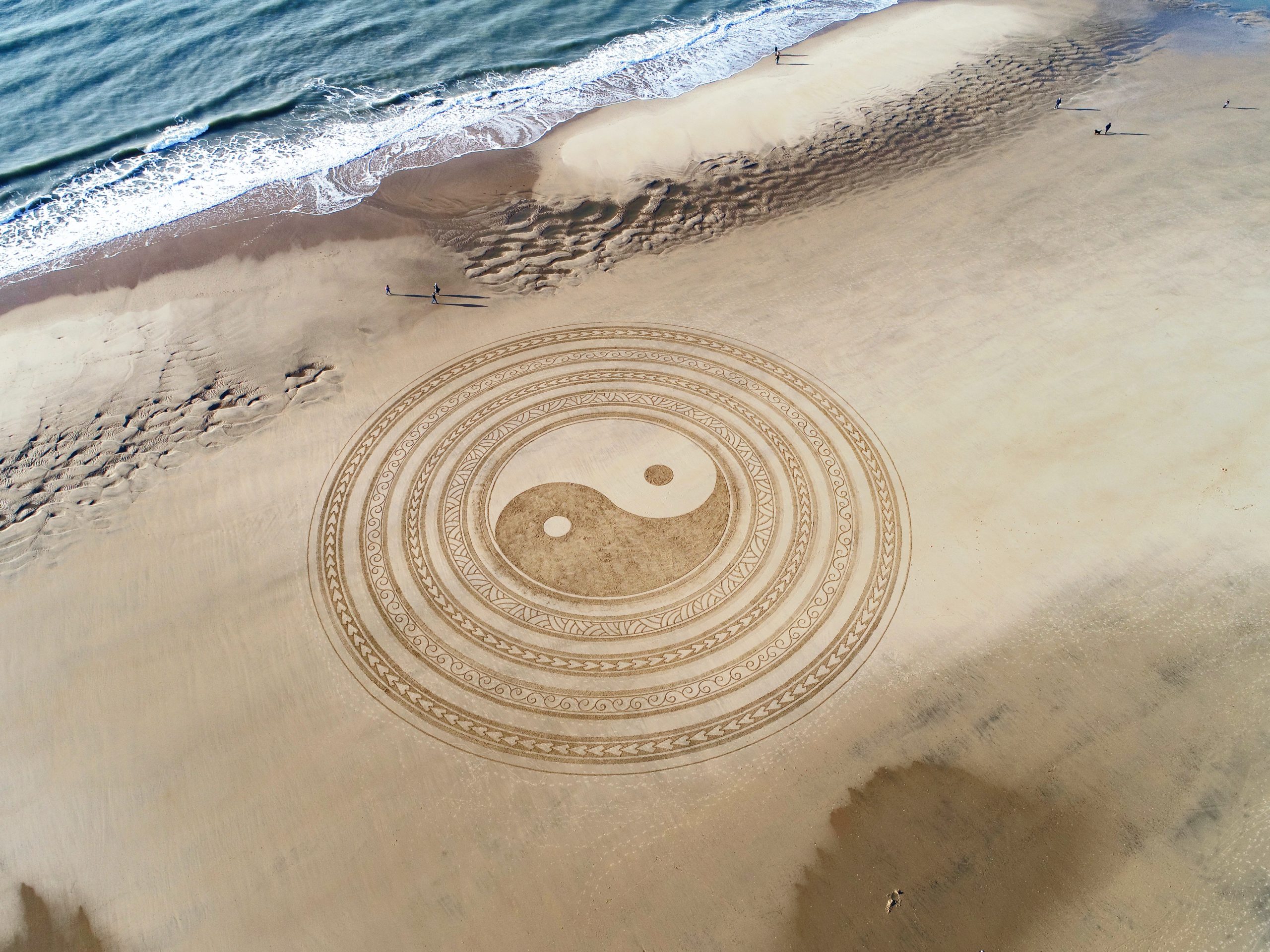 large yin yang symbol in sand on beach land art