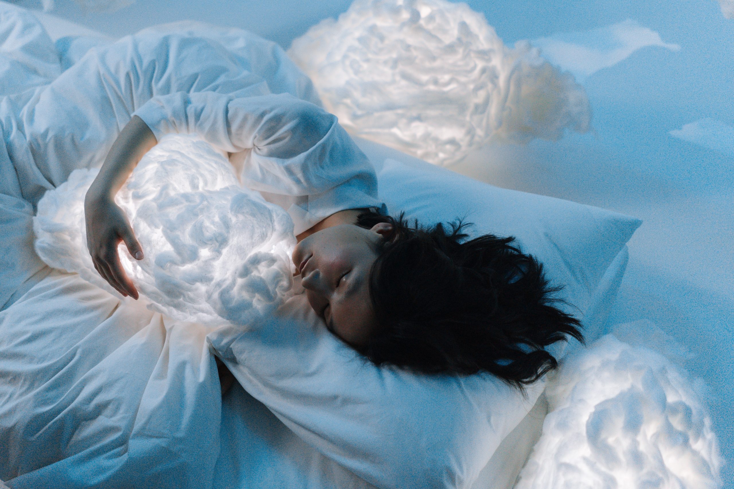woman holding luminous clouds while sleeping