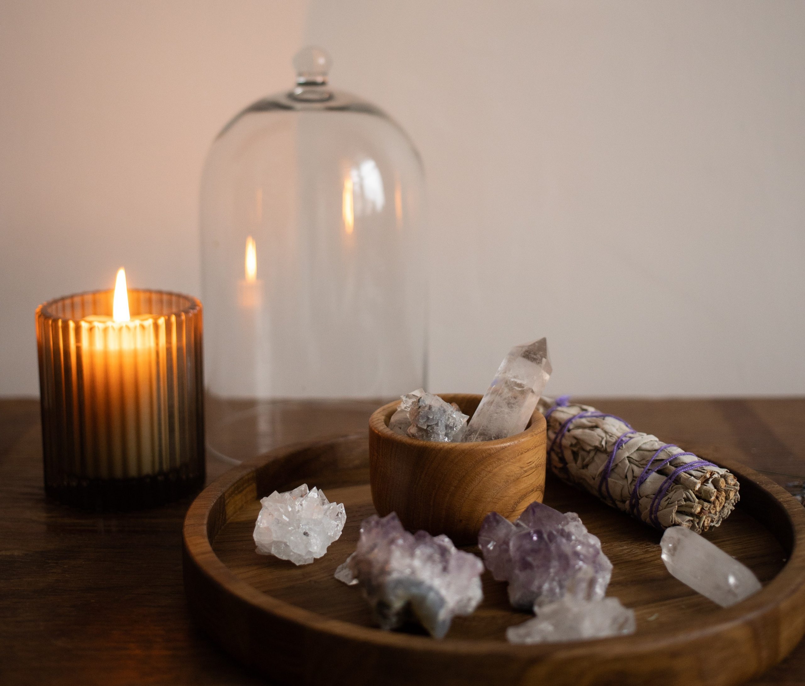 white sage smudge stick with candle and gemstones amethyst rock crystal in bell jar